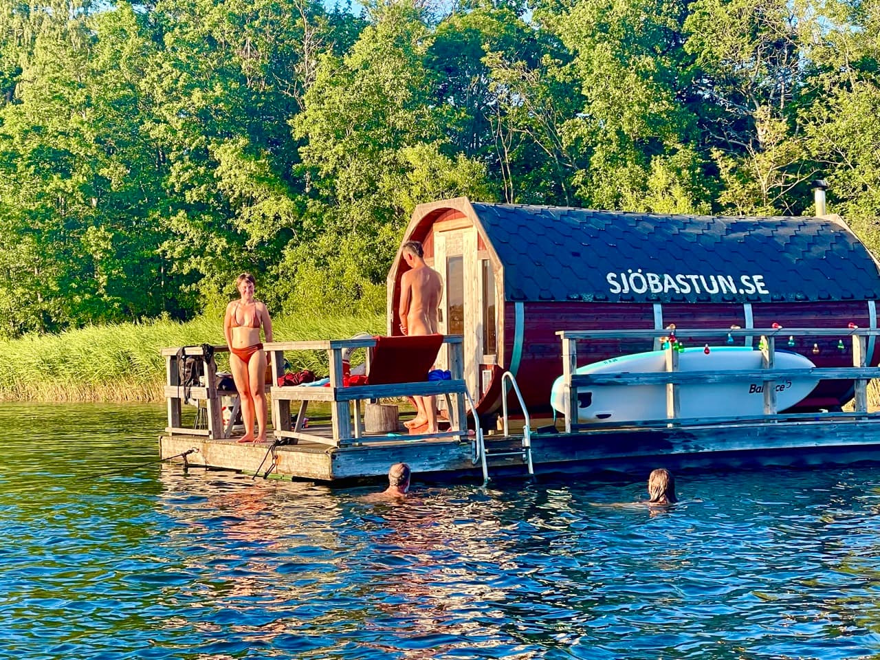 Gäster badar från bastuflotten i kvällssolen en sommardag