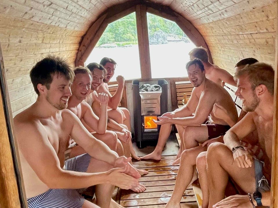 Ett glatt gäng på lavarna i den vedeldade bastun, med kaminen och sjöutsikten bakom