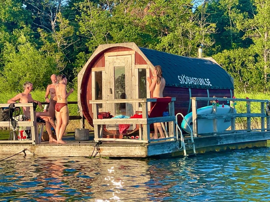 Gäster vilar på flottens däck mellan bastuvarven en sommarkväll
